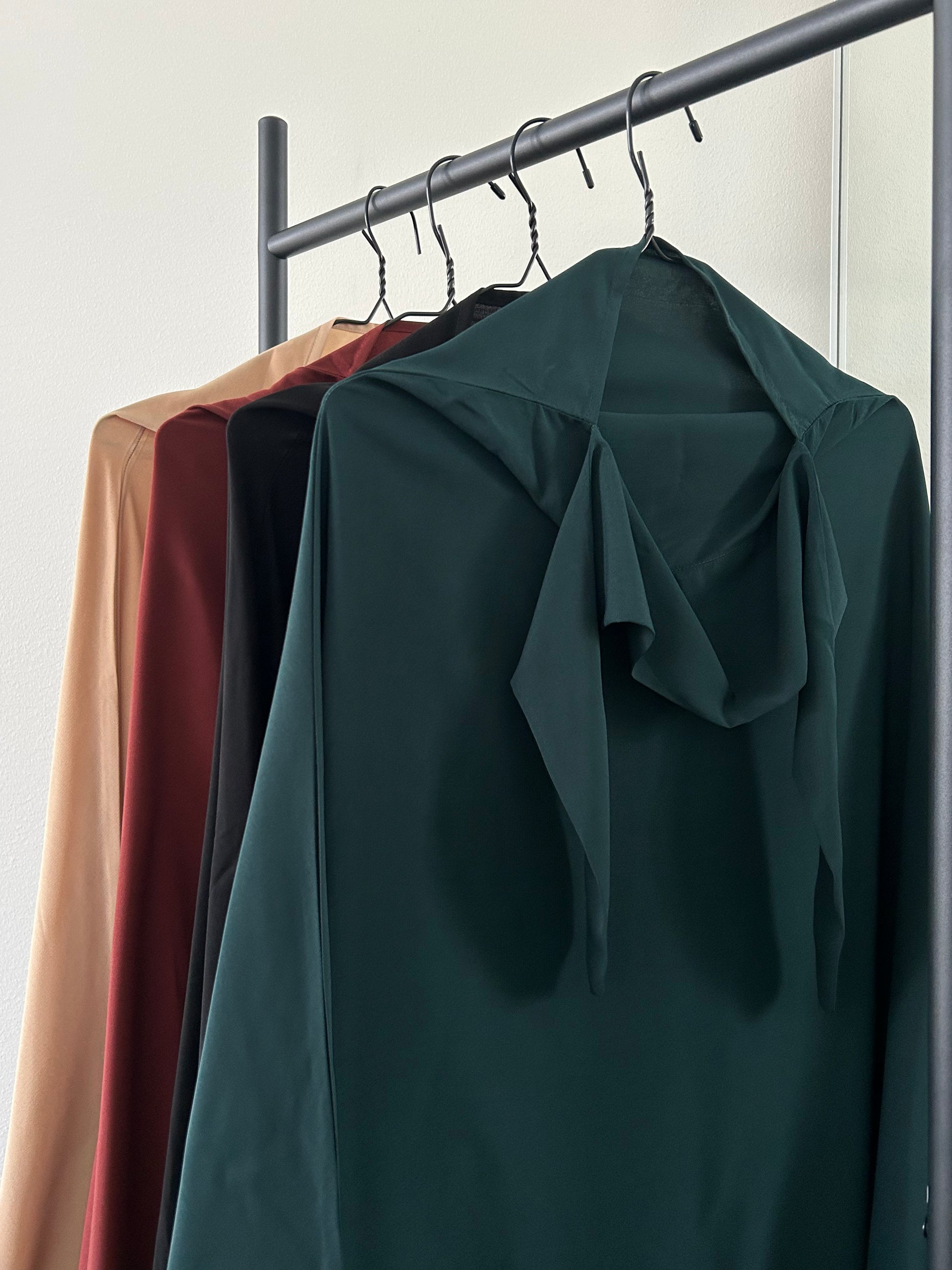 Layla Khimar Sets in various colors, including Autumn Ember, Deep Pine, Soft Camel, and Midnight Calm, displayed on hangers to showcase the range of rich, modest fashion tones by Lipes Modest Wear.